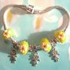 Charming Sunny-yellow  "wedding cake" style lampwork beads with white florets and red centers.  Charm bracelet with three "Dancing Girl" silver charms.  Bracelet clasp is engraved with the word : "LOVE."   Bracelet is approximately 8"