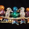 Five pretty rhinestone encrusted birds sitting on a branch.  Really vibrant shades of orange, aqua, turquoise, wine, etc.
Bracelet is a cuff style approximately 2 1/2" across at the cuff and 2" wide at the cuff.  Bird row is approximately 2 3/4" long, Approximately 1" wide.